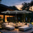 Patioslife grey patio umbrella with LED lights shading outdoor sofa set on garden decking at dusk
